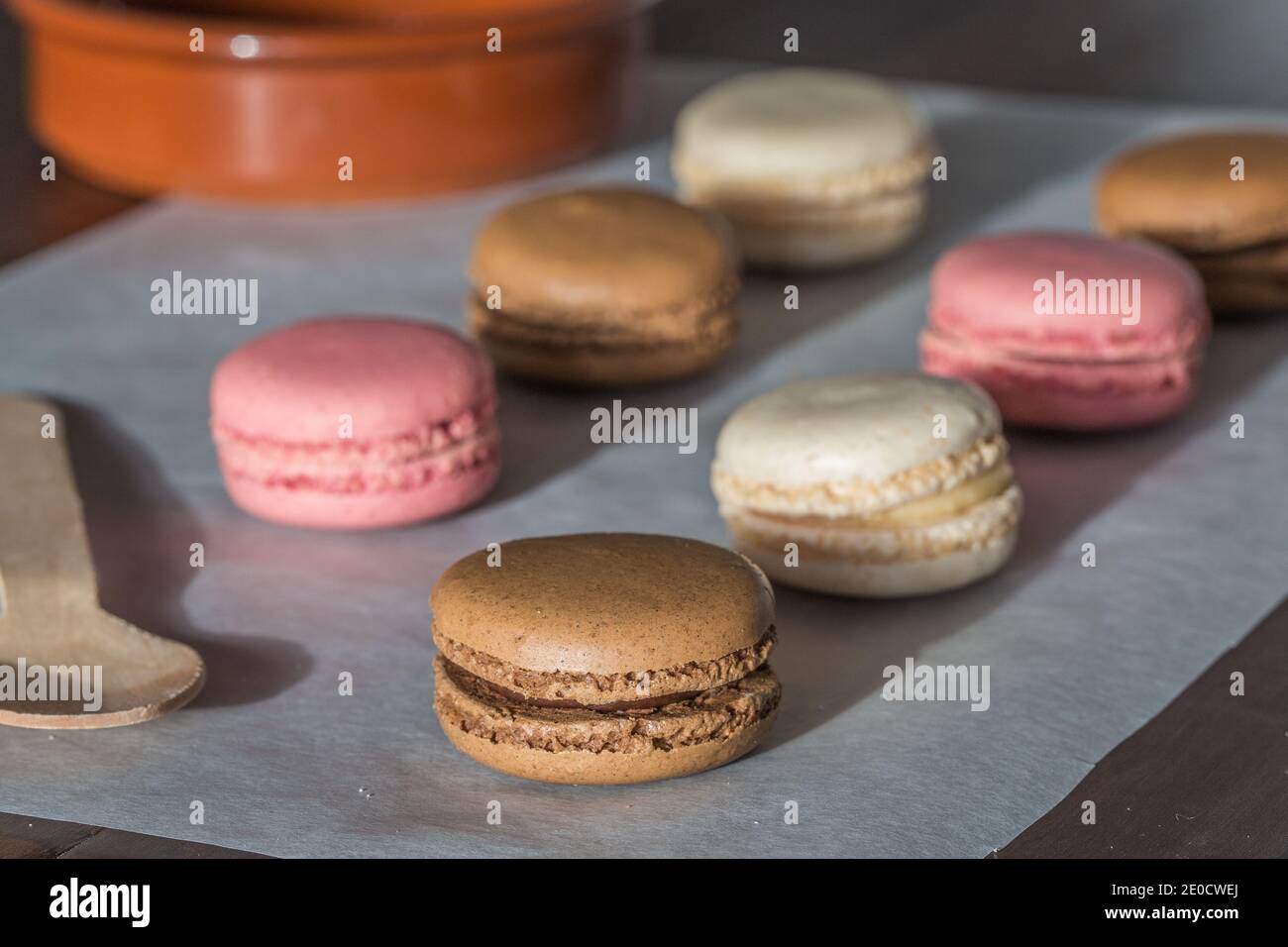 A close up food background of freshly baked homemade Macaroons or Macarons in Chocolate, Vanilla and pink Stock Photo