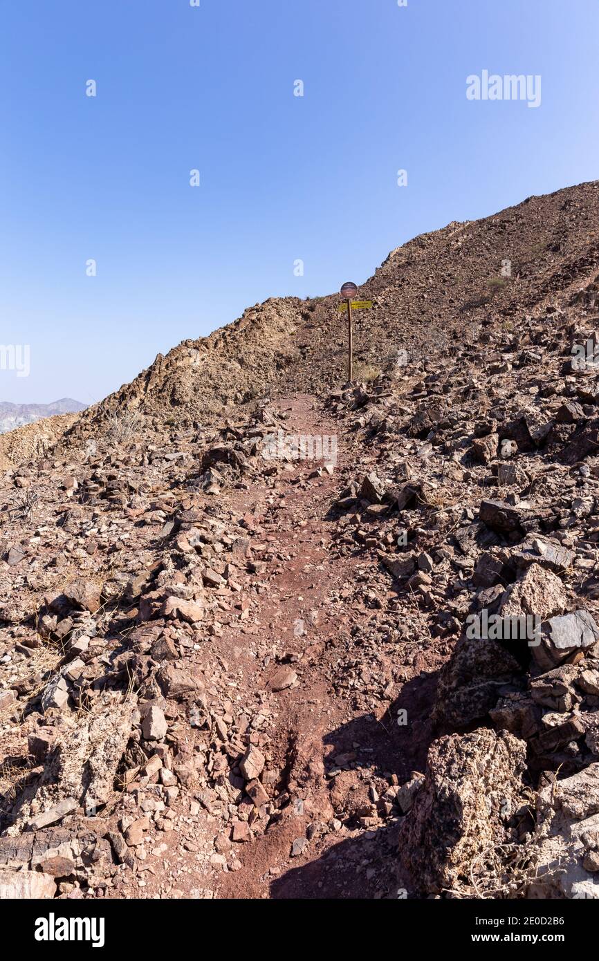 Rocky and stony mountain trail in Hatta Hajar Mountains (Hatta mountain sign hike), with directional signpost, United Arab Emirates. Stock Photo