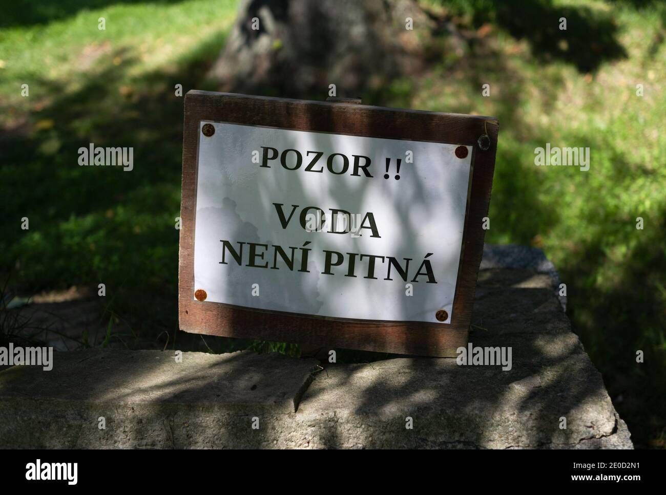 Signboard with text (translation from Czech: Warning. Not drinking water. Contrasty shadow in the nature. Very shallow focus. Stock Photo