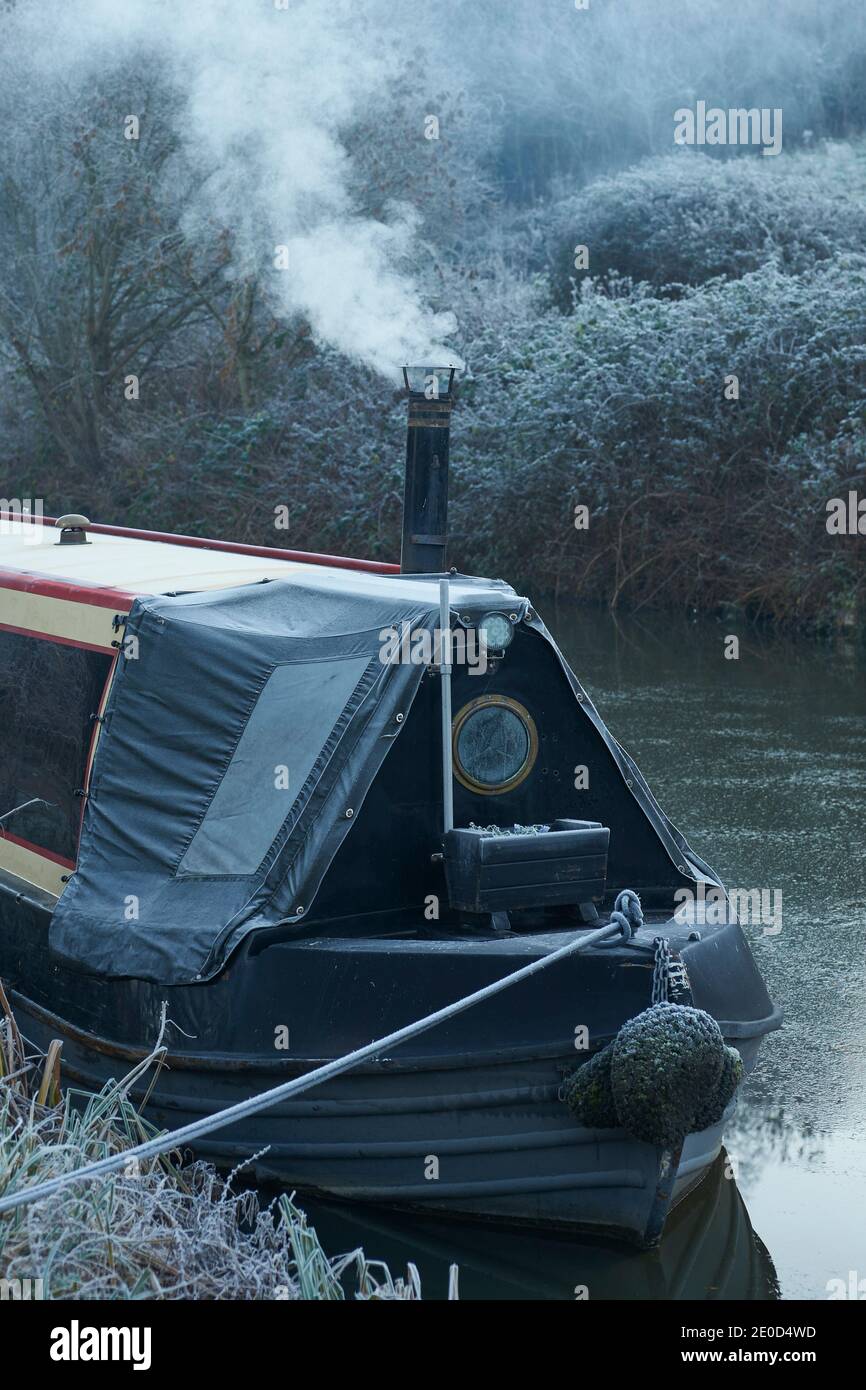 Smoke from the chimney of a narrowboat on a frosty morning along the Kennet  and Avon Canal near Bath in Somerset. Stock Photo
