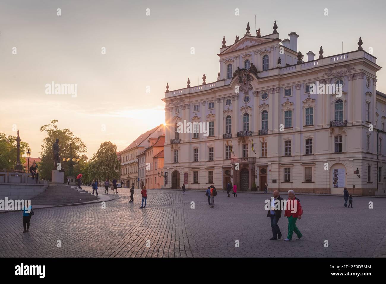Tourists enjoy the evening golden light outside the Archbishop Palace in Hradcany Square at the castle entrance in the capital city Prague, Czech Repu Stock Photo