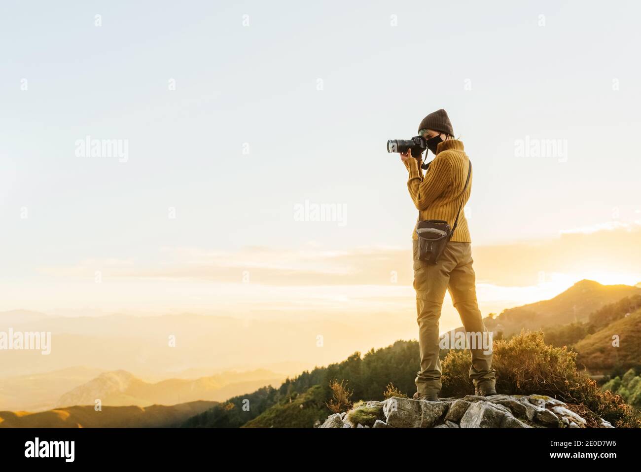 Photographer Back Back view of traveling photographer standing on rock and taking picture ...