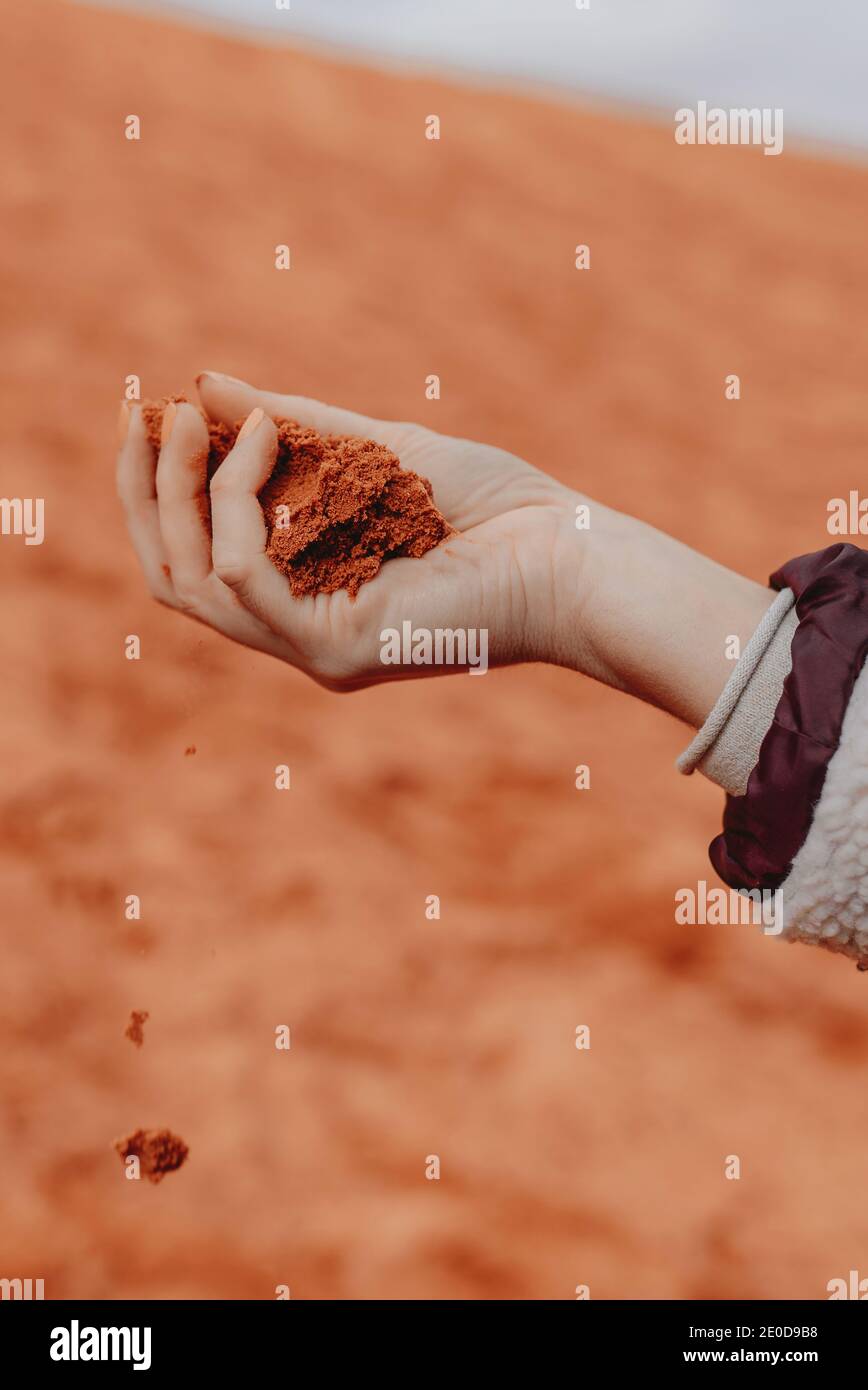 Unrecognizable crop person with handful of red sand standing in Wadi Rum dry valley in Jordan Stock Photo