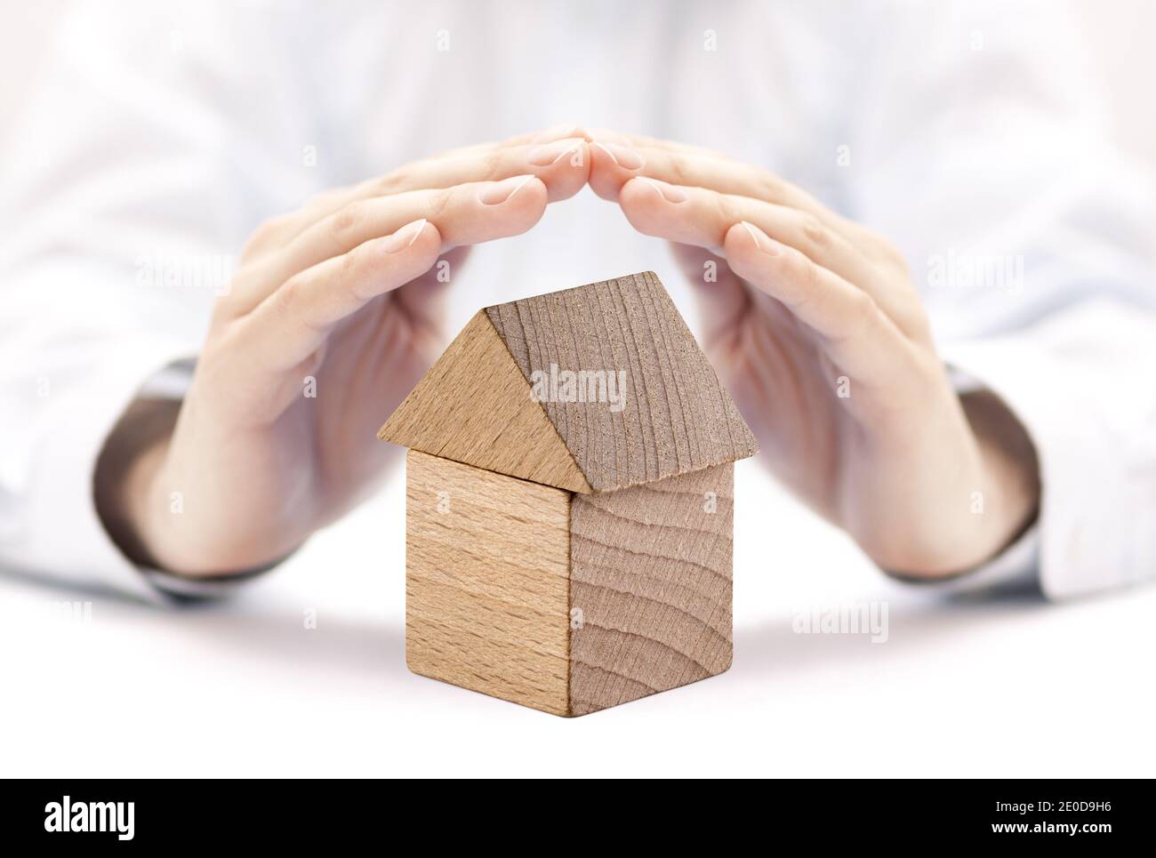 Small wooden house protected by hands. Home insurance concept Stock Photo