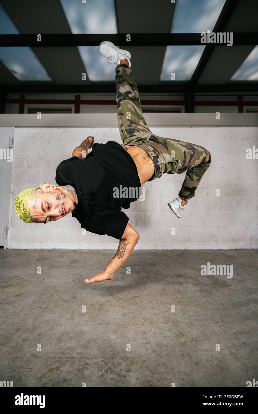 Full body of energetic young man doing acrobatic handstand while performing break dance Stock Photo