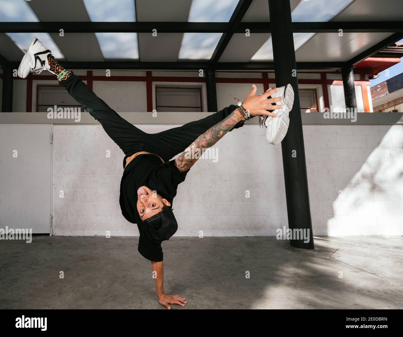 Full body of energetic young man doing acrobatic handstand while performing break dance Stock Photo