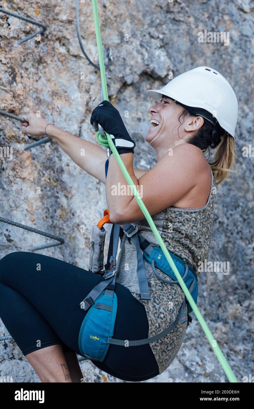 From below side view of determined active female climber in safety