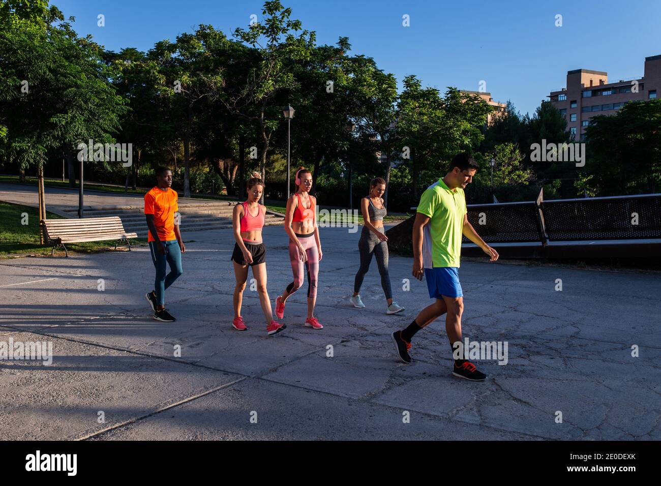 Company of diverse runners in sportswear walking together in city on sunny day after intense training Stock Photo