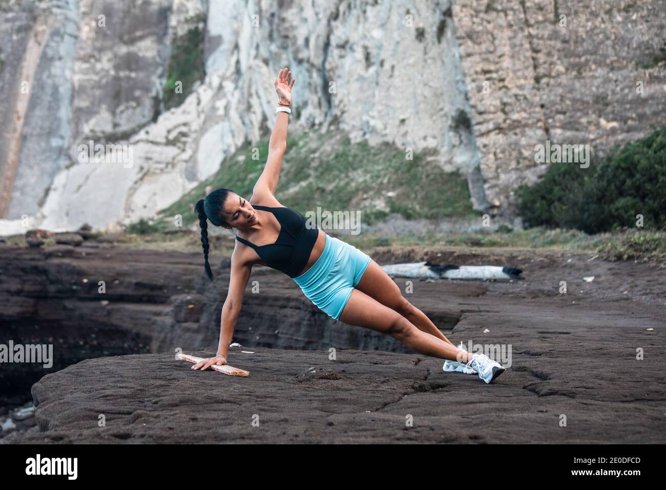 Determined female athlete balancing in side plank while doing exercises during workout at seaside Stock Photo