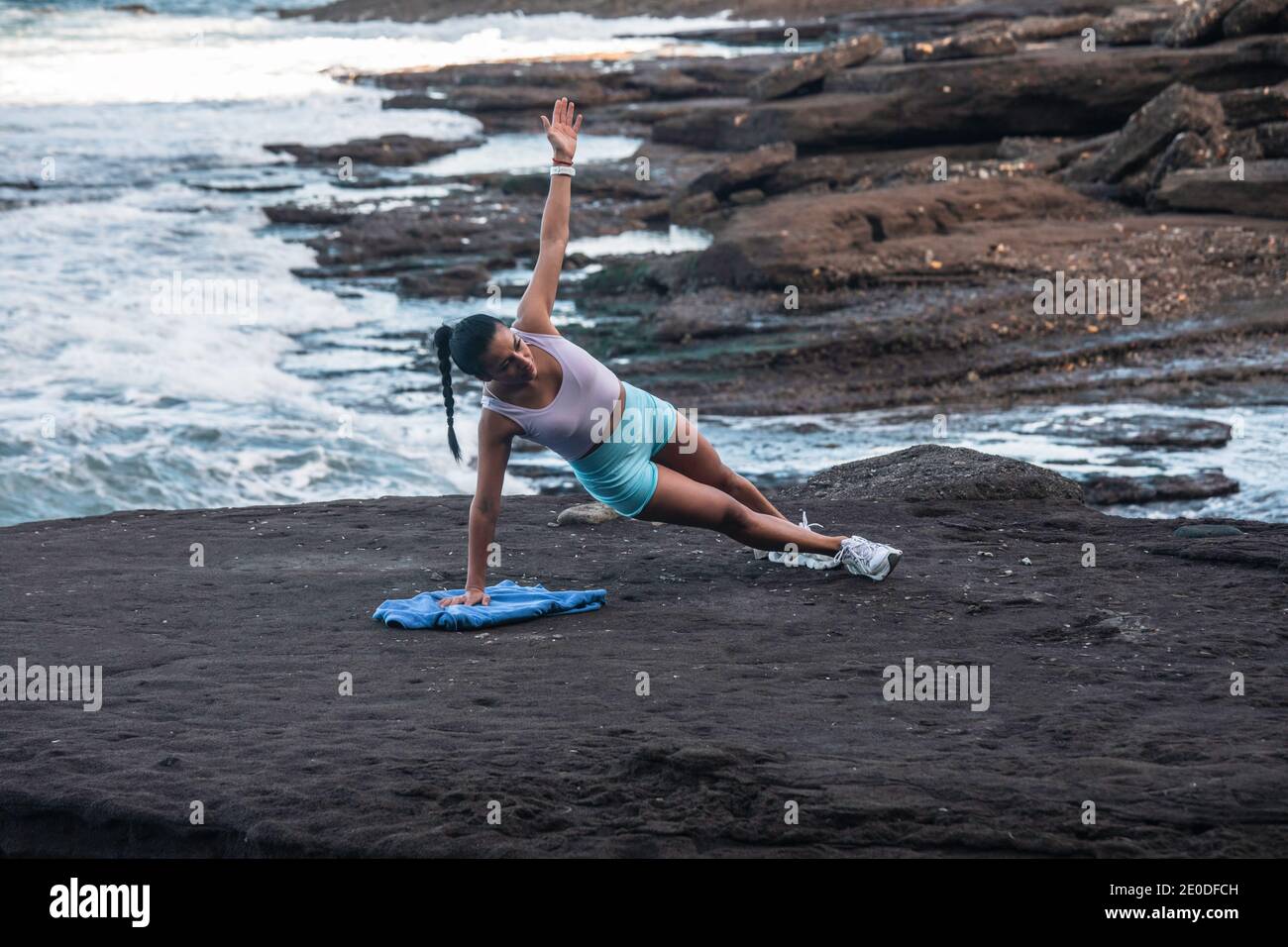 Determined female athlete balancing in side plank while doing exercises during workout at seaside Stock Photo