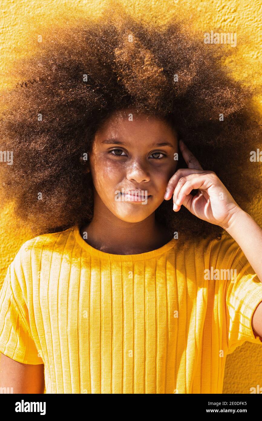 Teen African American girl with fluffy curly hair wearing yellow