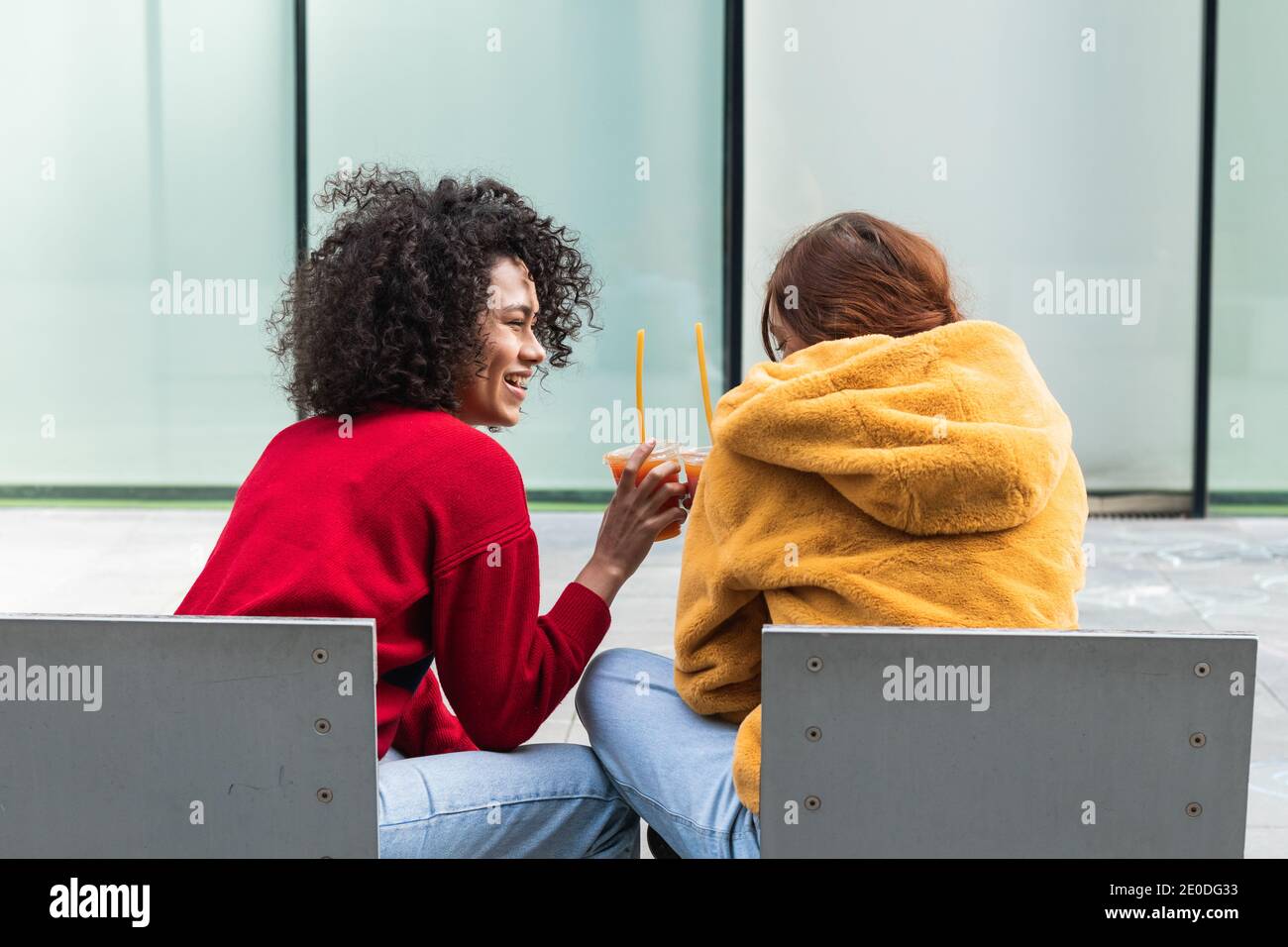 Thoughtful African American female with curly hair standing with crossed arms near glass building and looking away Stock Photo