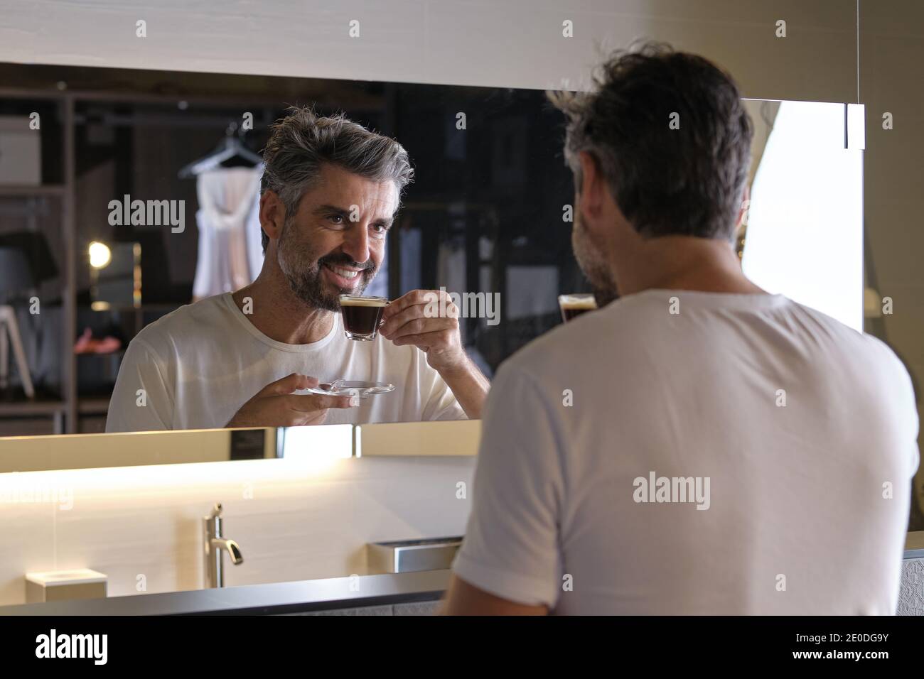Stock photo of middle age man having a coffee and looking himself in the mirror. Stock Photo