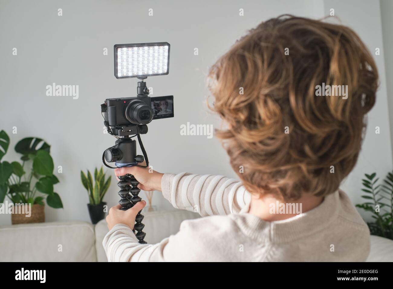 Back view of faceless boy making video in his house for his channel with modern equipment. Stock Photo