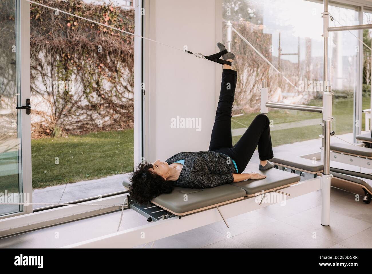 Side view of company of people in activewear lying on pilates reformer