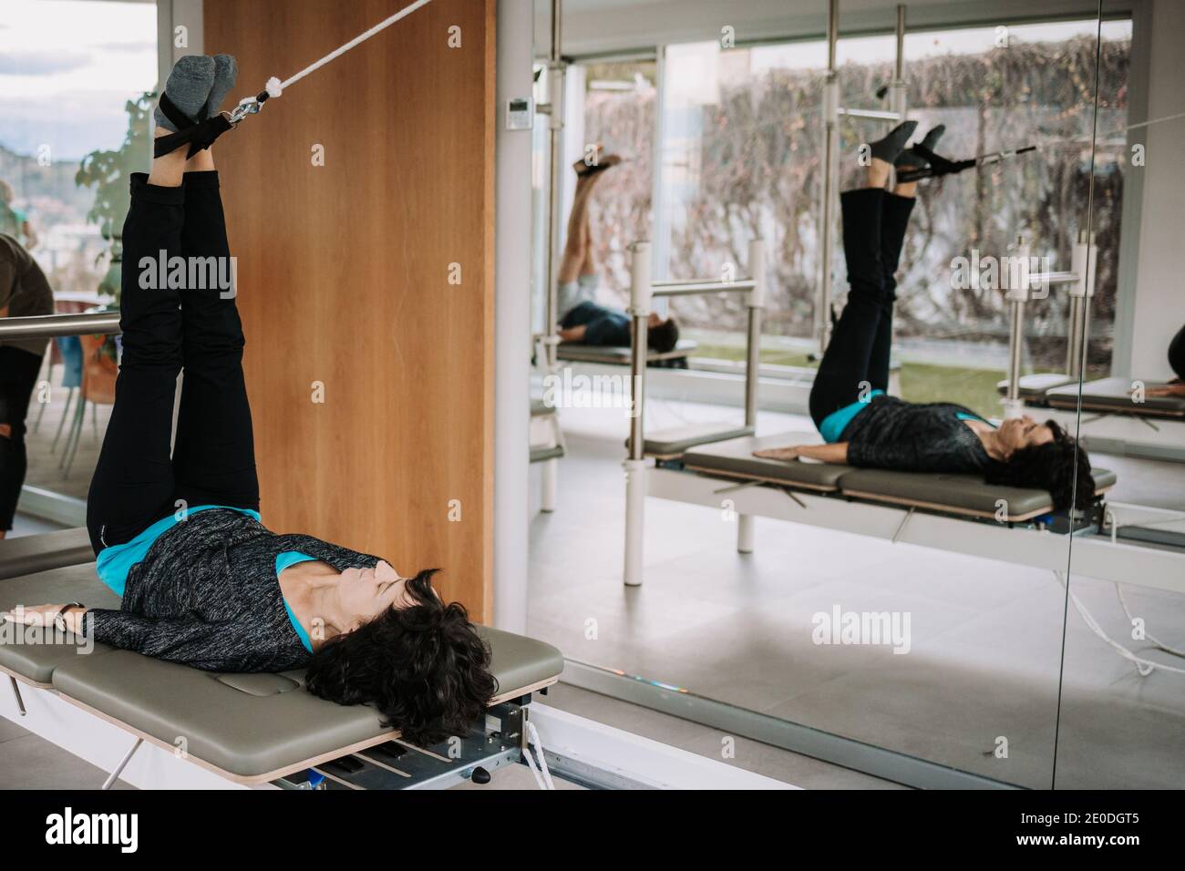 Side view of company of people in activewear lying on pilates reformer