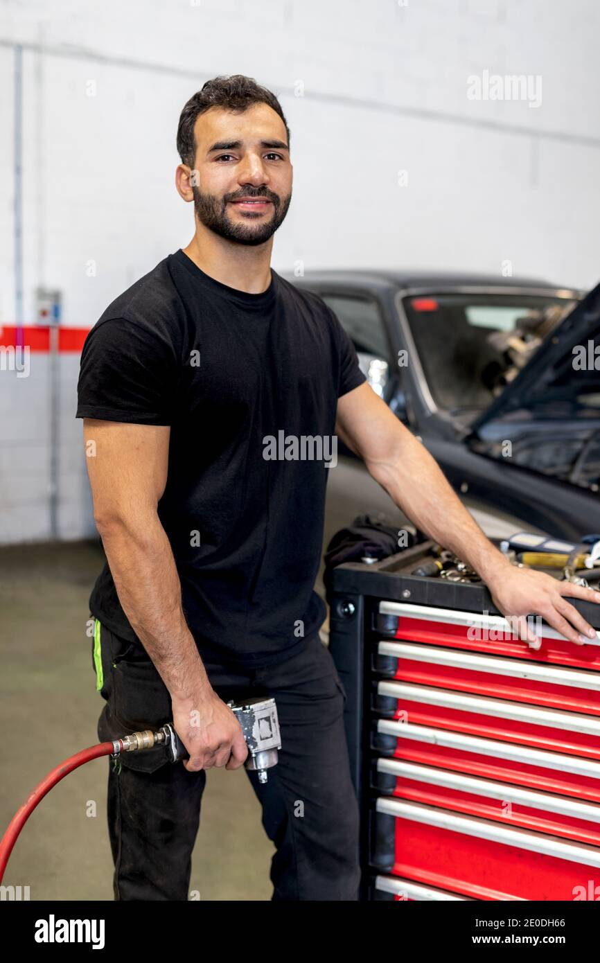 Male technician in gloves walking with tool in modern car