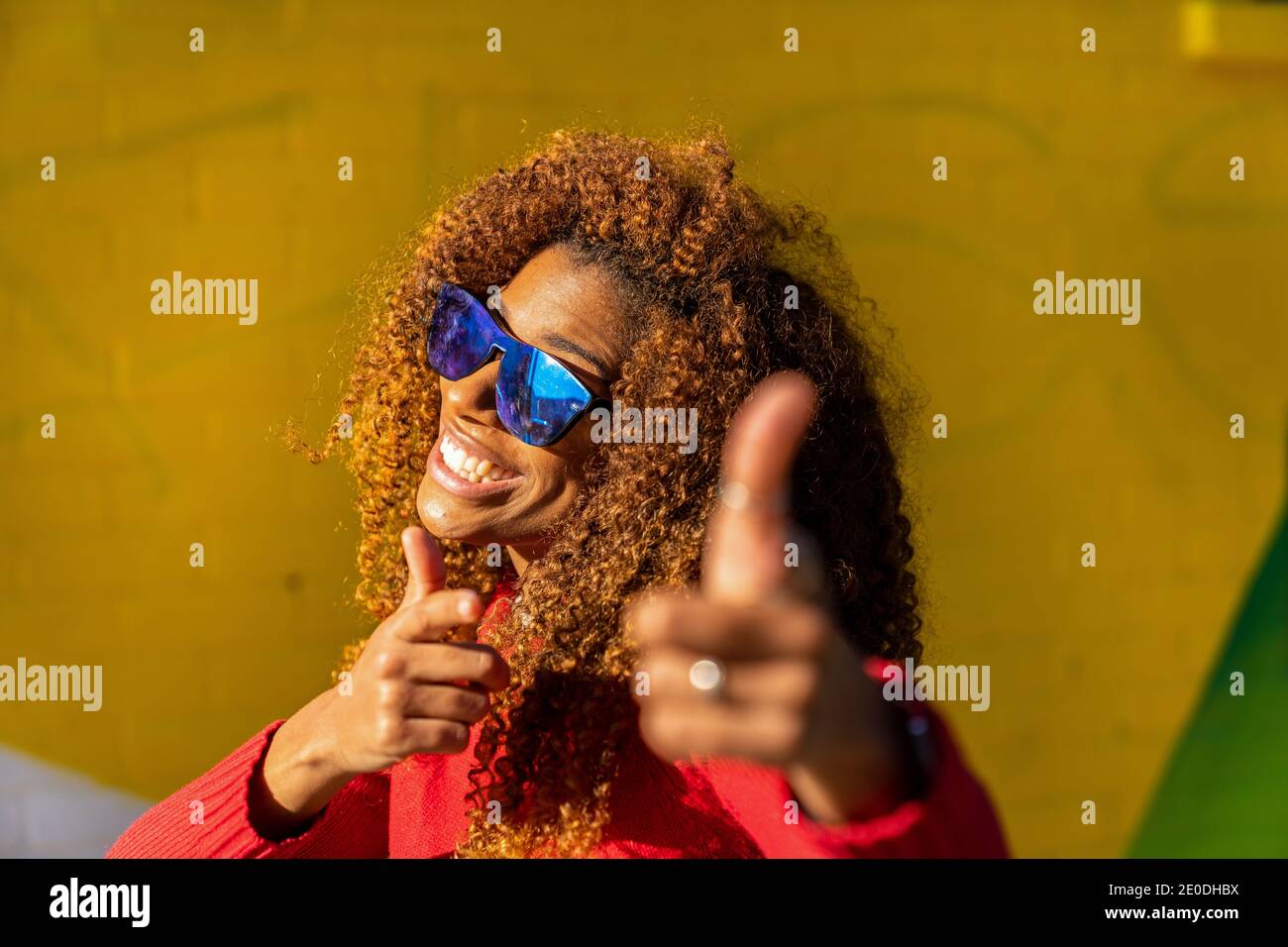 Cheerful young African American female with curly hair in casual ...