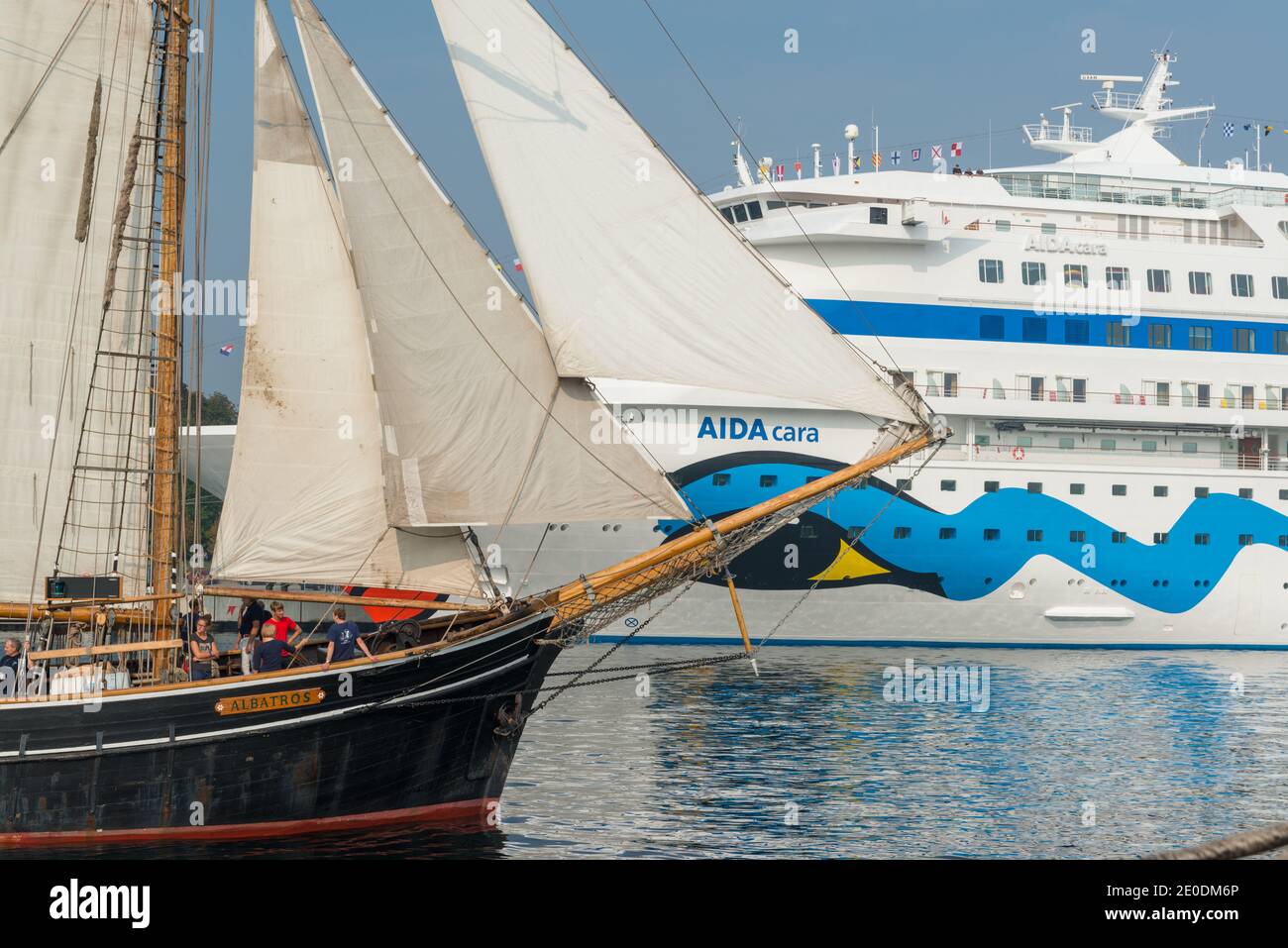 Ein Kreuzfahrtschiff der AIDA Cruises im Hafen von Kiel zu Gast, begleitet von einem Segelschiff mit gesetzten Segeln Stock Photo