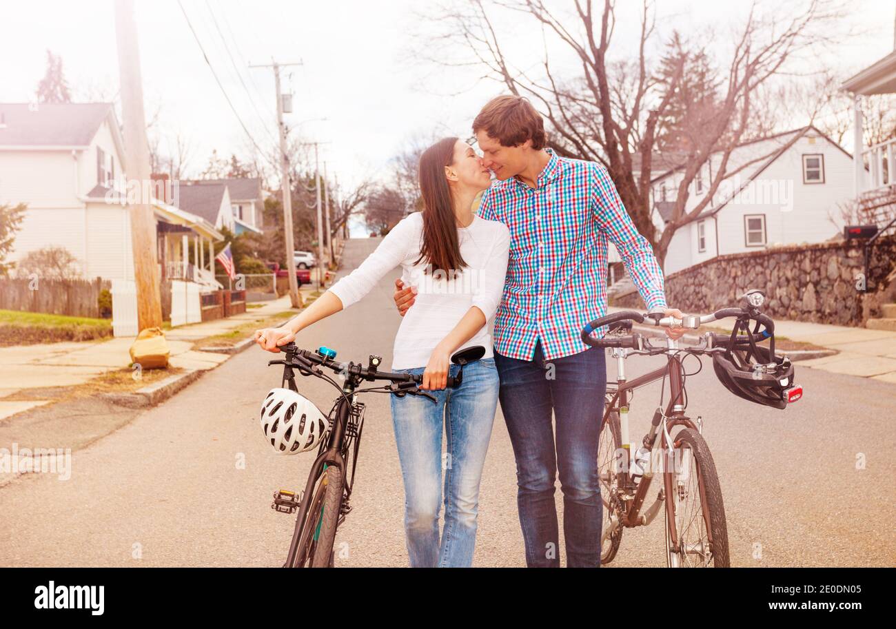 Kissing couple walking on the urban street holding bikes and hugging Stock Photo