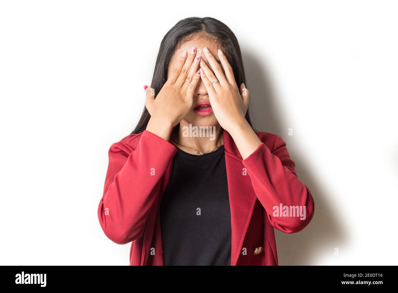 Asian woman covers her face with her hands on white background Stock Photo