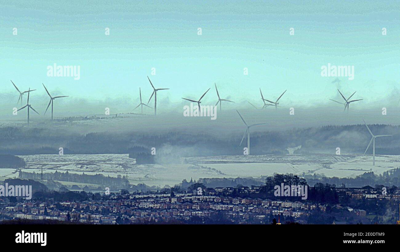 Glasgow, Scotland, UK. 31sth December, 2020. UK Weather: Freezing weather over Whitelee Windfarm  saw snow and mist as the wind turbines turned in the largest onshore wind farm in the UK as new year beckons to the south of the city pictured from 10 miles away. Credit: Gerard Ferry/Alamy Live News Stock Photo