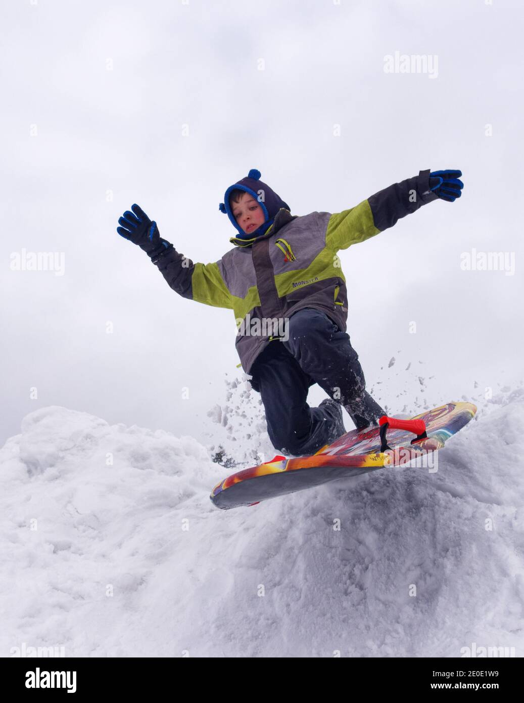 A young boy (8 yr old) doing jumps on his sledge in winter in Quebec Stock Photo