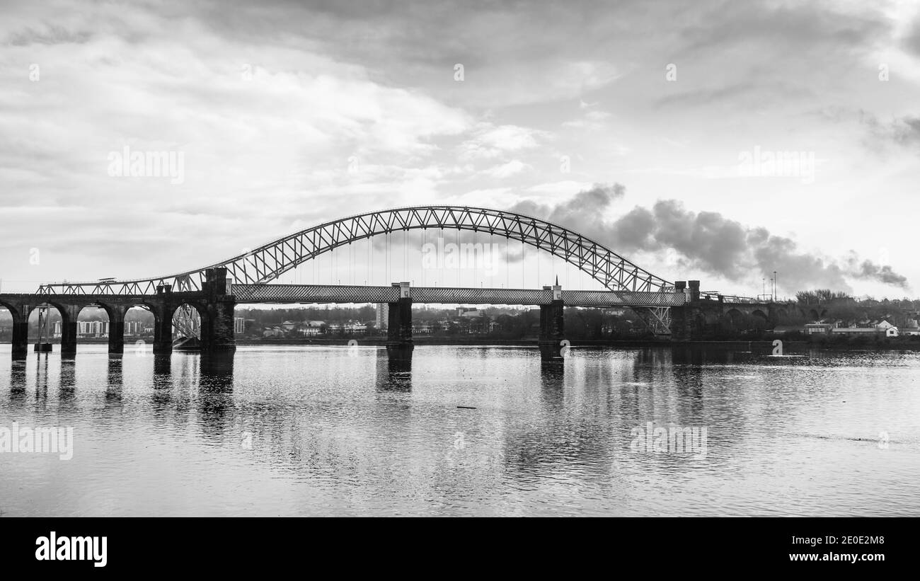 The iconic bridges linking Runcorn and Widness span the Mersey Estuary.  The Runcorn Railway Bridge sits closest to the camera and the Silver Jubilee Stock Photo