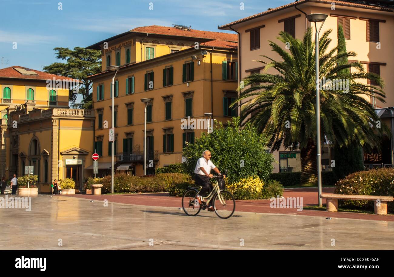 Piazza del Popolo in Montecatini Terme, Tuscany. A beautiful marble piazza with cafes and hotels.  Active senior riding bicycle, sunny day. Stock Photo