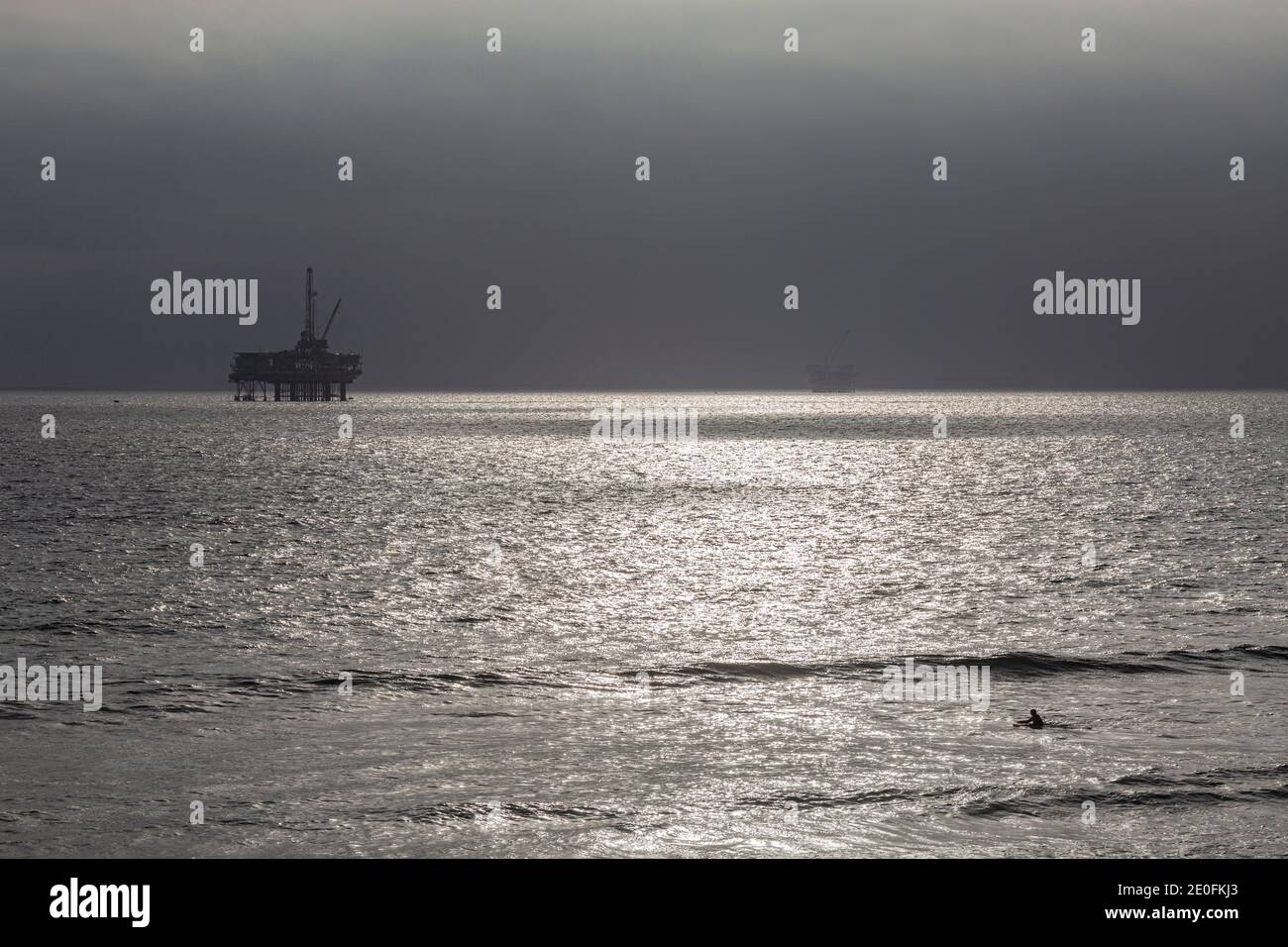 Oil Derrick and surfers off coast of Huntington Beach, Orange County, California, USA Stock Photo