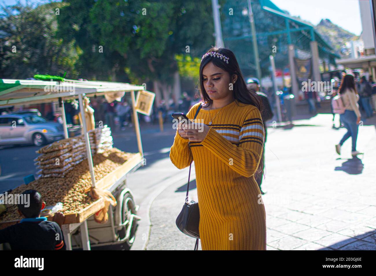 HERMOSILLO, MEXICO DECEMBER 31: People walk the streets of downtown for year-end shopping. Daily life of Hermosillenses, during the last day of the year on December 31, 2020 in Hermosillo, Mexico. new year (Photo by Luis Gutierrez / Norte Photo)  HERMOSILLO, MEXICO DICIEMBRE 31: Personas caminan por las calles del centro de la ciudad para las compras de fin de año. Vida cotidiana de hermosillenses, durante el ultimo dia del año el 31 de Diciembre 2020 en Hermosillo, Mexico.  año nuevo (Photo by Luis Gutierrez/Norte Photo).. . Una joven mujer camina escribiendo mensajes de texto en su telefomno Stock Photo