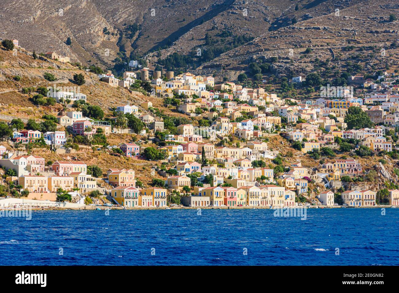 Late afternoon sun over neo-classical mansions of Gialos and the old hillside Horio, Symi Island, Dodecanese, Greece Stock Photo
