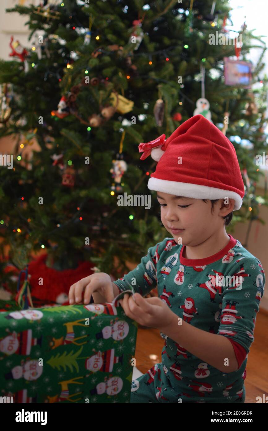 Boy Opening Christmas Presents With Santa Hat Stock Photo