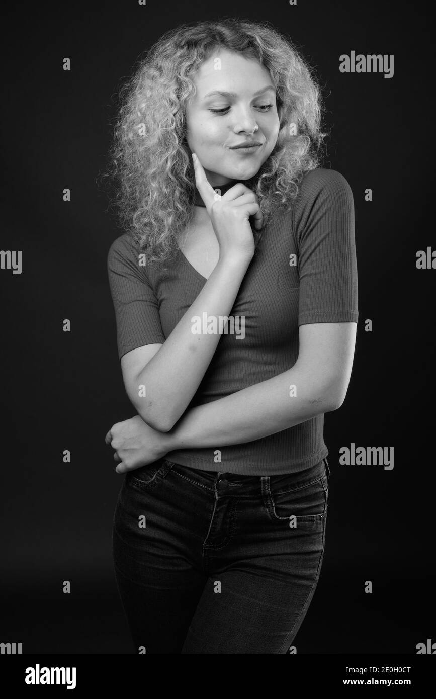 Young beautiful woman with blond curly hair against gray background Stock Photo