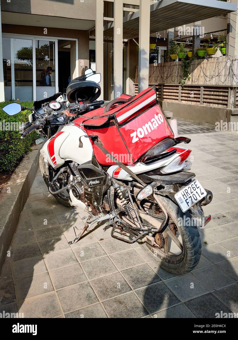 motorcycle rider with red zomato bag delivering food to a urban