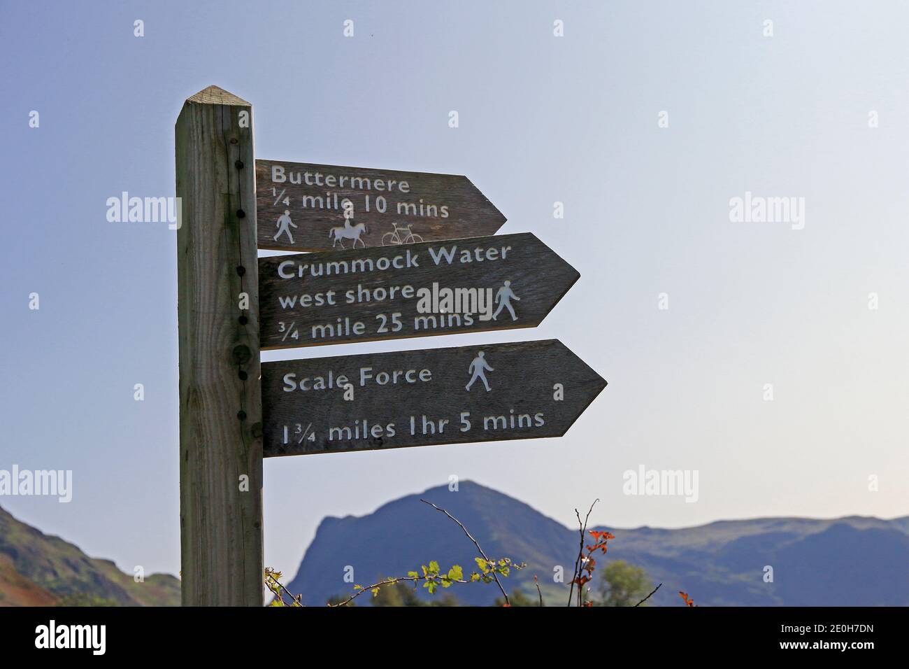 Wooden signpost showing destinations and walking times, Buttermere Stock Photo