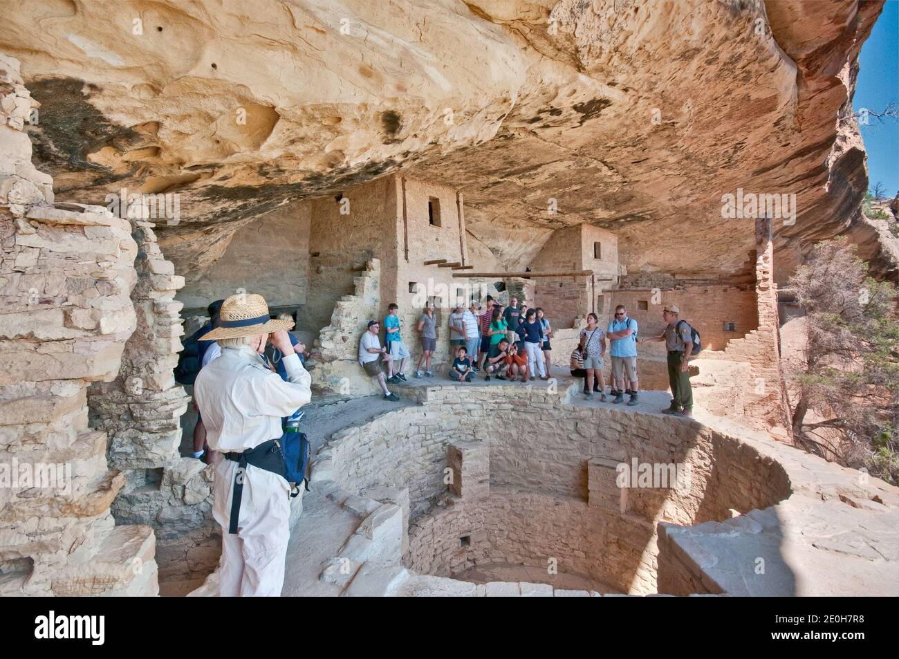 Park guide and visitors over kiva (ceremonial chamber) at Balcony House cliff dwelling, Cliff Palace Loop, Mesa Verde National Park, Colorado, USA Stock Photo