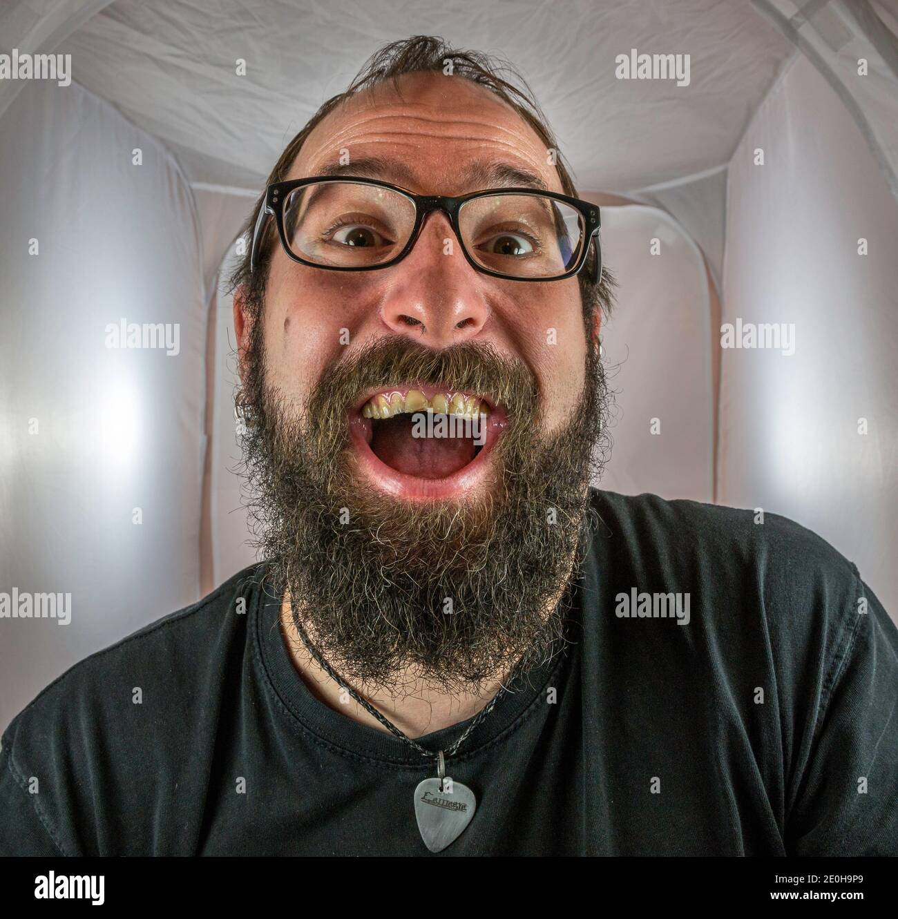 A bearded gleeful and gloating man in a good mood with black glasses Stock Photo