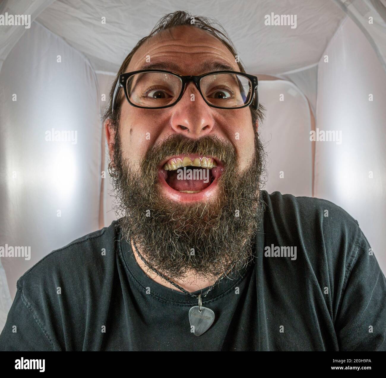 A bearded gleeful and gloating man in a good mood with black glasses Stock Photo