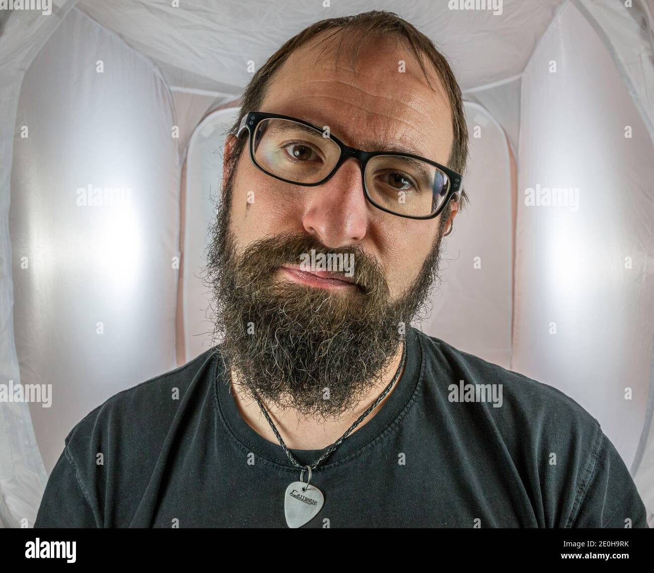 A bearded and annoyed looking man with black glasses Stock Photo