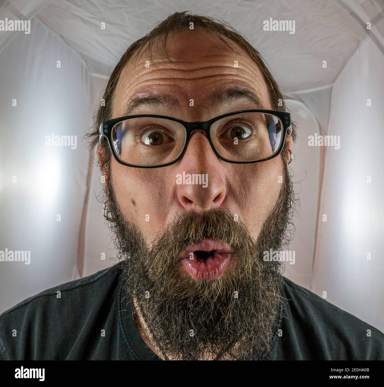 A surprised looking bearded man with glasses Stock Photo