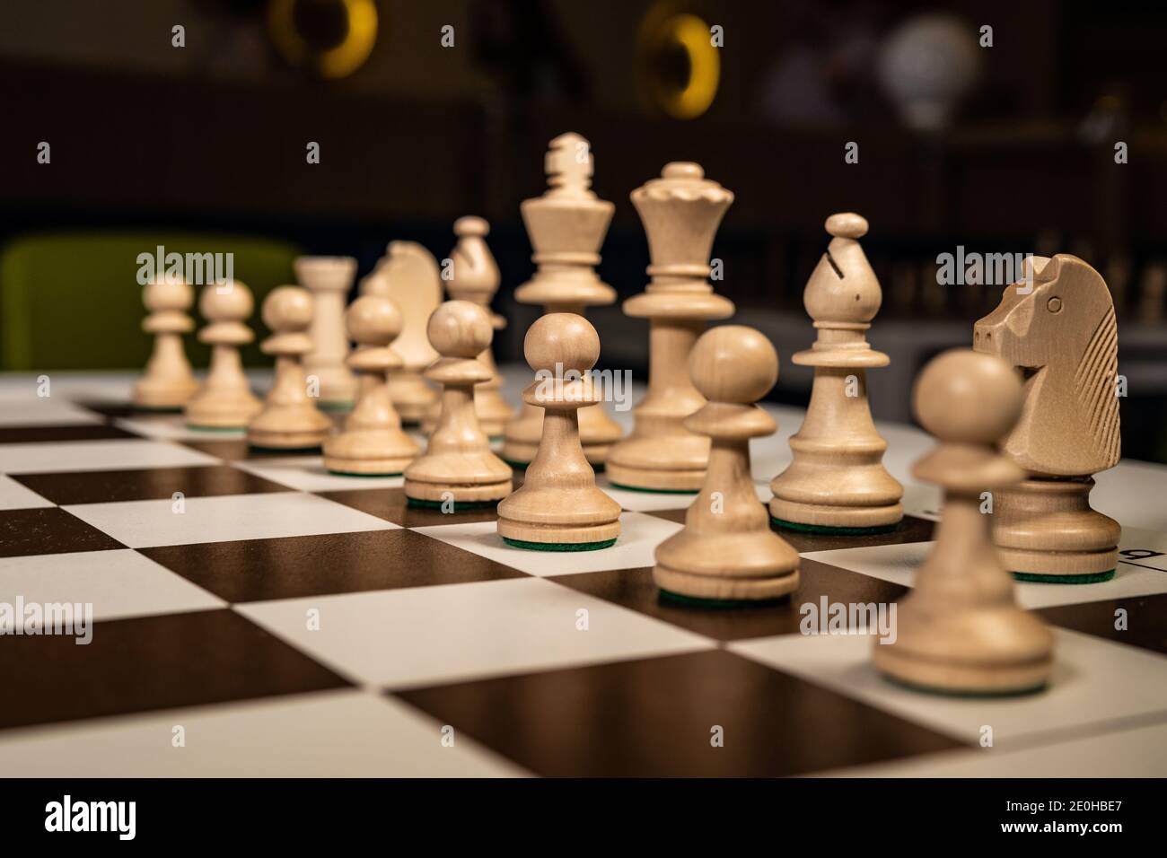 Play wooden chess on a platform in a checkered ivory, pawns and rooks, queens and kings, horses table in the dark, stylish for advertising design. Stock Photo