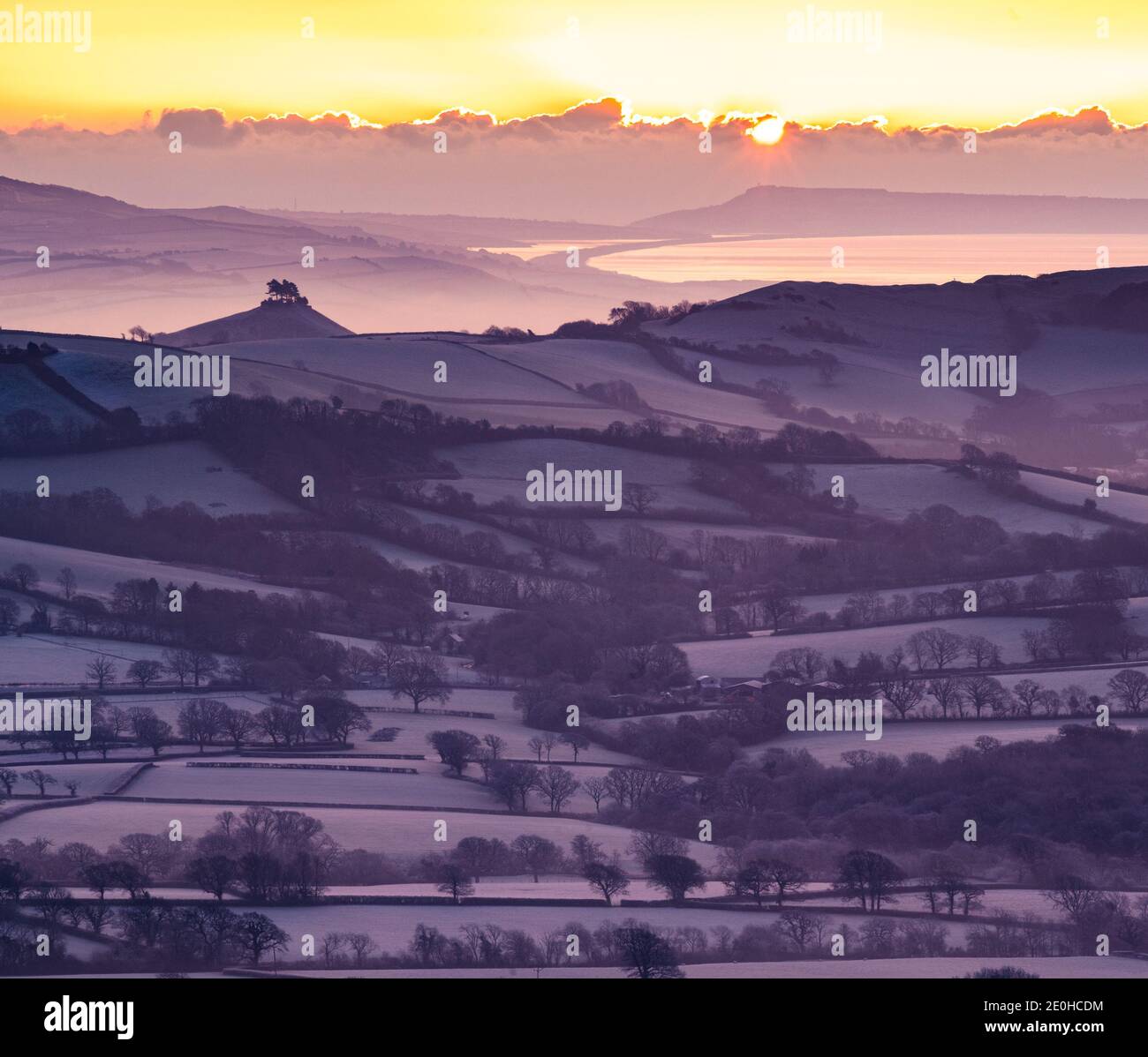 Lamberts Castle, Dorset, UK. 1st Jan, 2020. UK Weather: 2021 gets off to a glorious start as the sun rises over a frosty Marshwood Vale with Colmers Hill, Portland and Chesil beach seen in the distance. Credit: Celia McMahon/Alamy Live News Stock Photo