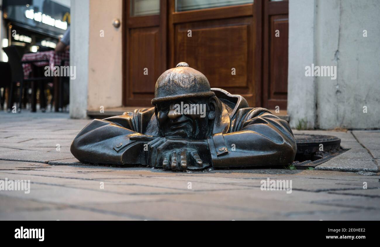Cumil Man at work bronze statue sculpture artwork in old town city center of Bratislava in Slovakia Stock Photo