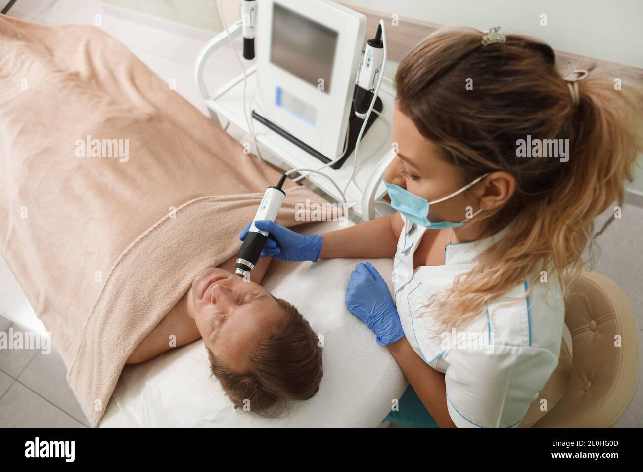 Top view shot of a professional cosmetologist wearing medical face mask while working with male client Stock Photo