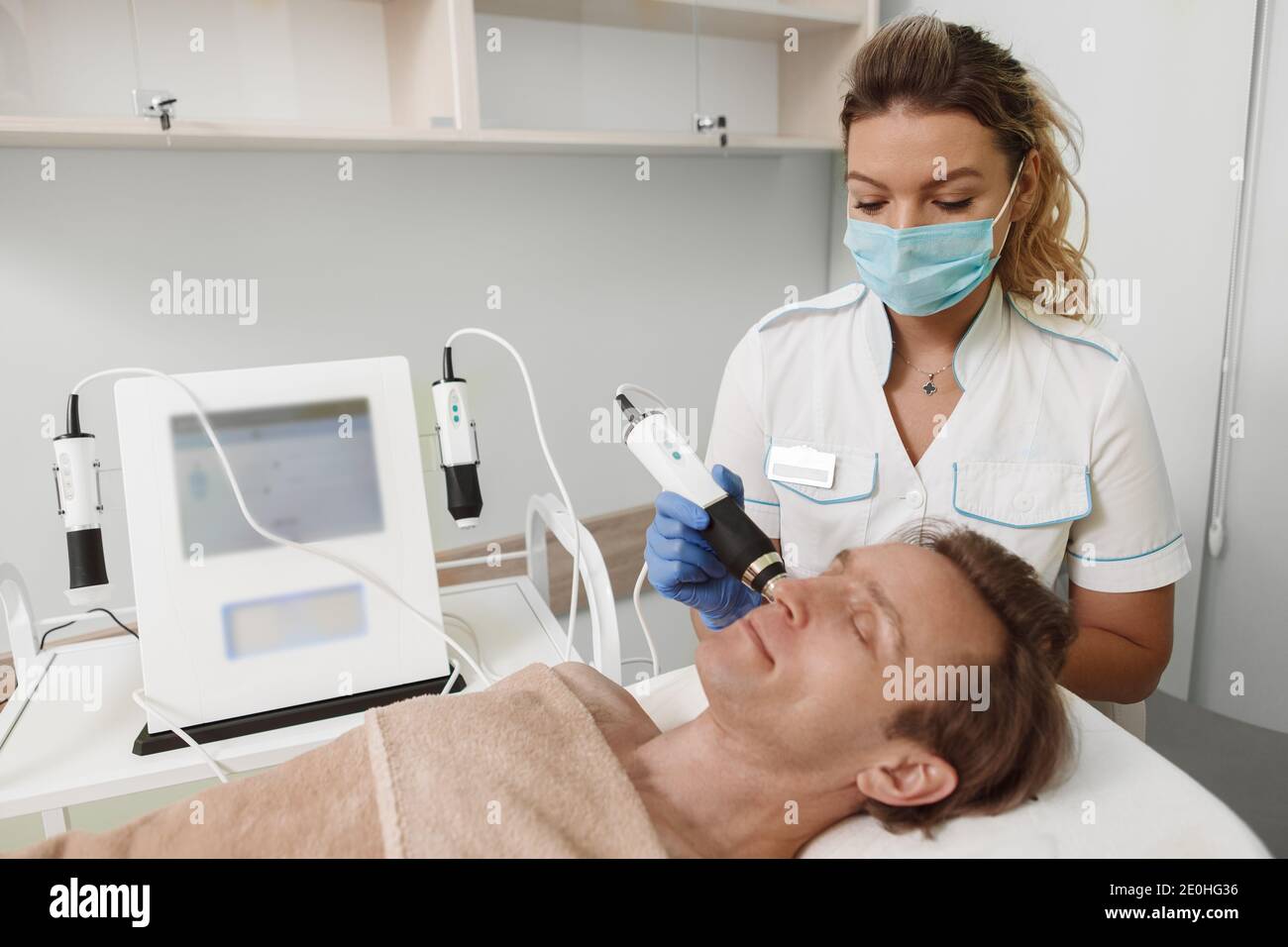 Professional cosmetologist working during pandemic, wearing medical face mask at her beauty clinic Stock Photo