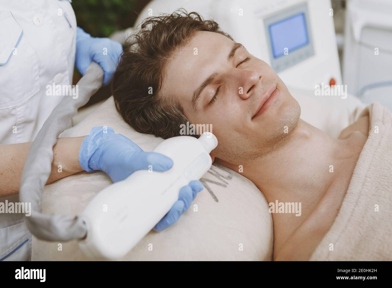 Close up of a handsome relaxed man receiving facial laser treatment at
