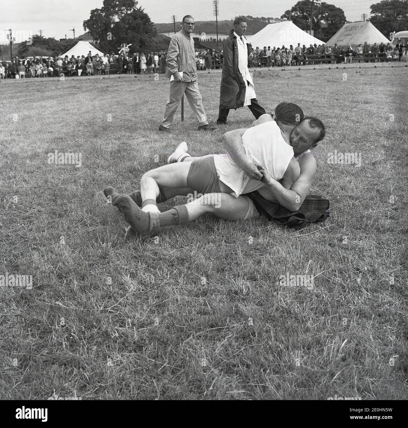 1960s, historical, two men wrestling on the grass at the Highland Games, Scotland, UK, with one man wearing just underpants, while the other has a kilt on. Stock Photo