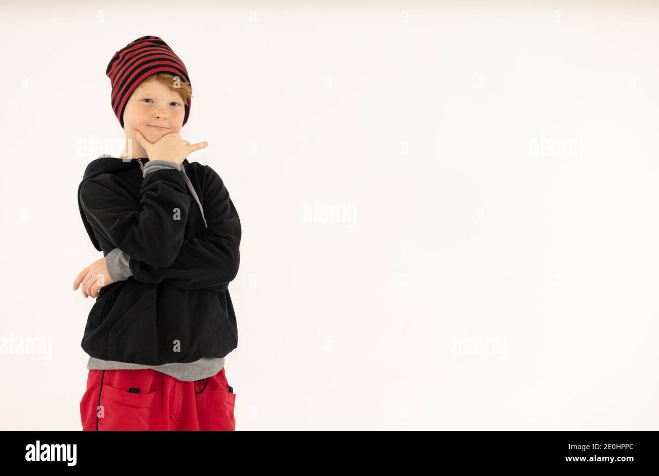 a boy with red hair in a cap poses on a white background Stock Photo
