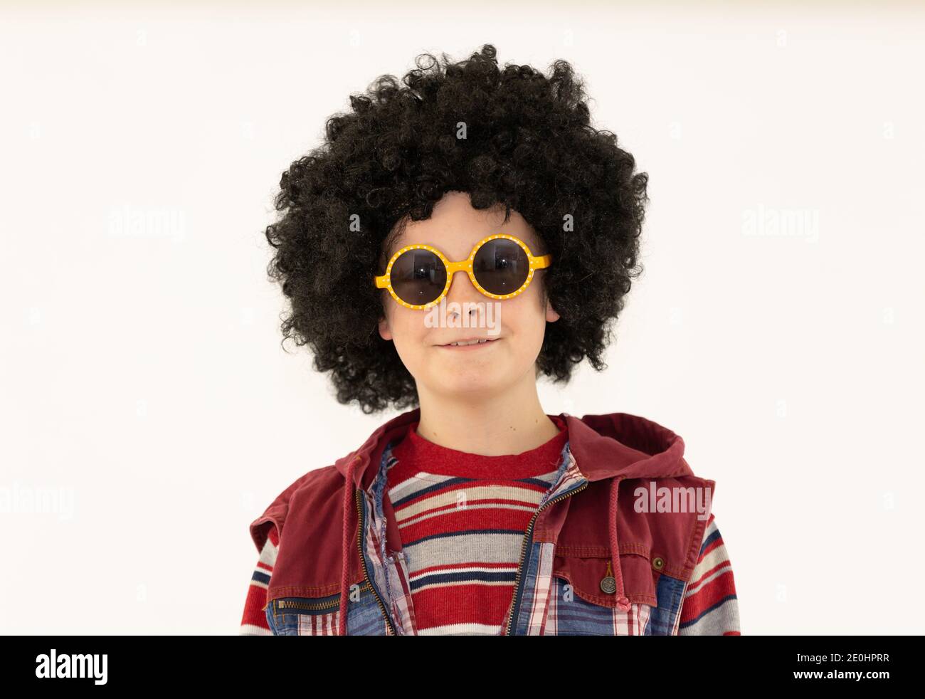 boy in afro hairstyle on a skateboard poses on a white background, boy in sunglasses young Stock Photo
